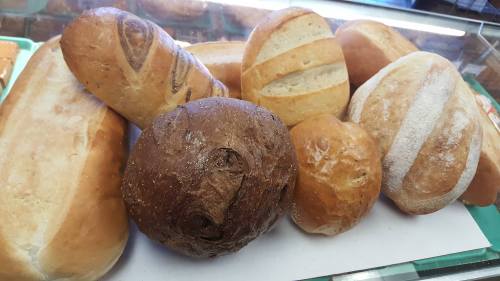 A variety of freshly baked breads, including loaves and rolls, displayed on a tray.