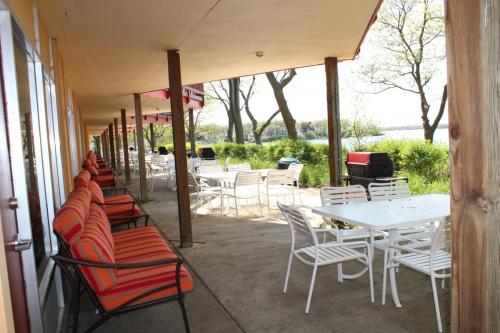 A lakeside patio with colorful chairs and tables, surrounded by greenery and trees.