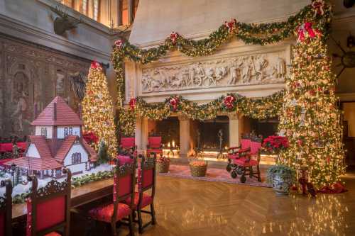 A festive room with decorated Christmas trees, a gingerbread house, and a beautifully adorned fireplace.