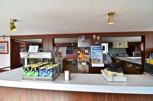 A concession stand featuring popcorn, snacks, and drinks, with a rustic wooden counter and decor.