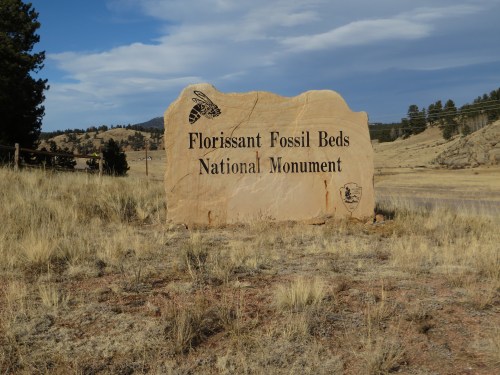 Sign for Florissant Fossil Beds National Monument, set against a grassy landscape and blue sky.