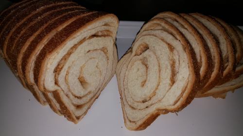 Sliced loaf of bread with a spiral pattern, showcasing soft white interior and golden-brown crust.