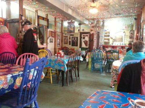Colorful diner interior with vibrant tables, string lights, and patrons enjoying the cozy atmosphere.
