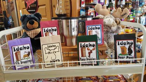 A display of Idaho-themed snacks and a mug, featuring plush bear and moose toys on a shopping cart.