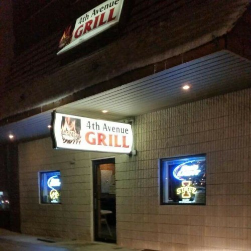 Exterior of 4th Avenue Grill at night, featuring illuminated signs and a welcoming entrance.