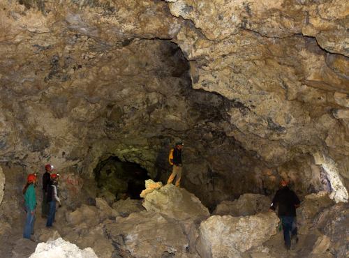 A group of people exploring a rocky cave with uneven terrain and natural stone formations.