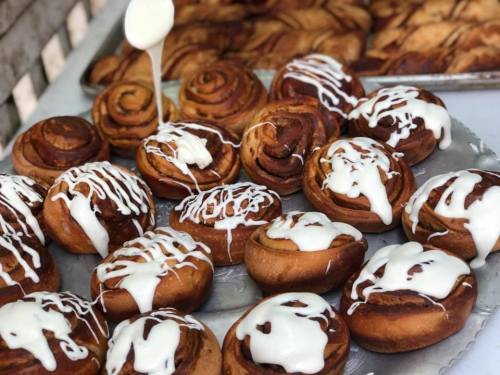 Freshly baked cinnamon rolls drizzled with creamy icing, arranged on a tray.
