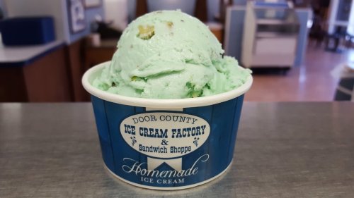 A cup of mint green ice cream with chunks, labeled "Door County Ice Cream Factory & Sandwich Shoppe."