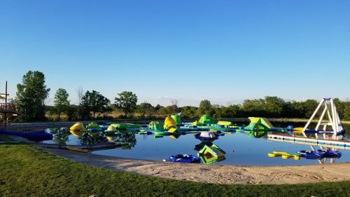 A sunny outdoor pool area with inflatable water toys and a clear blue sky in the background.