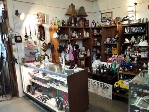 A cozy vintage shop filled with various collectibles, decor items, and a display case showcasing jewelry and trinkets.