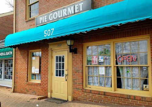 A brick storefront with a teal awning reading "Pie Gourmet" and an "OPEN" sign in the window.