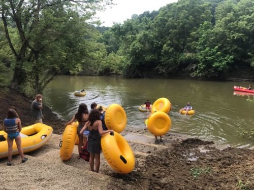 People preparing to launch yellow inflatable rafts into a river surrounded by lush greenery.