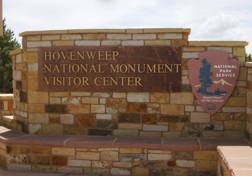 Sign for Hovenweep National Monument Visitor Center, featuring stonework and the National Park Service emblem.