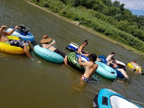 A group of people relaxing on colorful inner tubes in a river, enjoying a sunny day.
