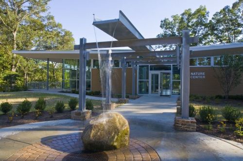 Modern nature center building with a water feature and landscaped entrance.