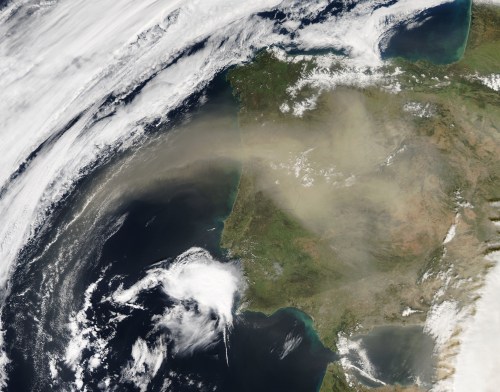 Satellite image of the Iberian Peninsula, showing land, clouds, and a haze over the region.