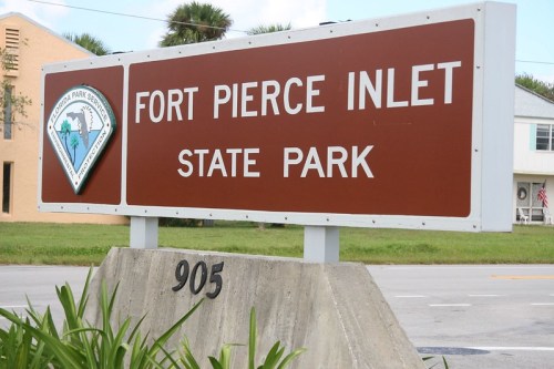 Sign for Fort Pierce Inlet State Park, featuring the park logo and the address 905, surrounded by greenery.