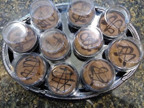 A tray of individual chocolate desserts in clear cups, each topped with a decorative chocolate drizzle.