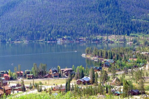 A scenic view of a lake surrounded by lush forests and quaint houses along the shoreline.