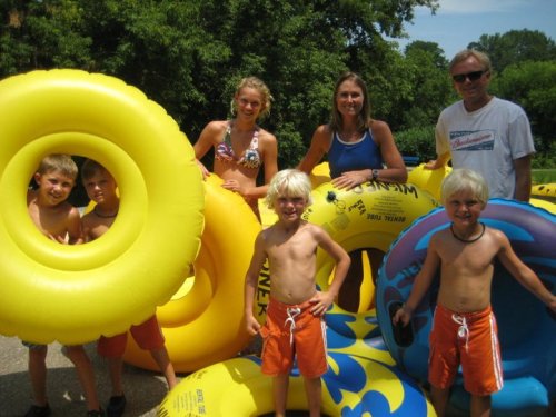 A group of children and adults pose with colorful inner tubes on a sunny day, ready for a water adventure.