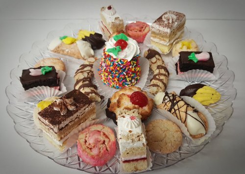A decorative platter filled with an assortment of colorful pastries and desserts, including cakes and cookies.
