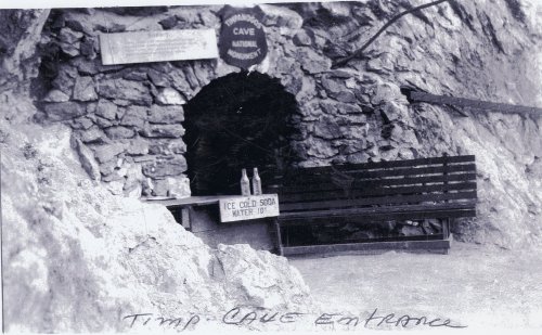 Entrance to Timp Cave, featuring a stone archway, a bench, and a sign for ice-cold soda and water.