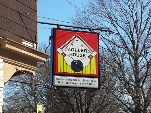 Sign for Holler House, featuring bowling pins and a ball, noting it's home to the oldest sanctioned bowling alleys.