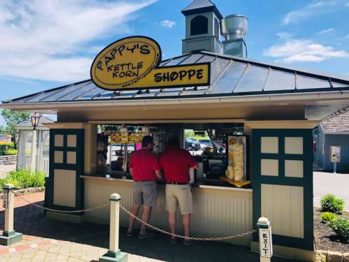 Two customers in red shirts order at Pappy's Kettle Korn Shoppe, a charming outdoor snack stand.