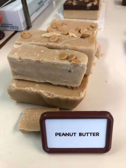 A stack of peanut butter fudge pieces with a sign labeled "PEANUT BUTTER" in front.
