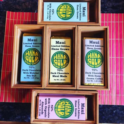 Five bars of Hana Gold chocolate in wooden boxes, featuring flavors like dark chocolate with coffee and sea salt.