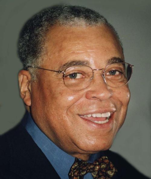 A smiling older man with glasses and gray hair, wearing a blue shirt and a patterned bow tie.