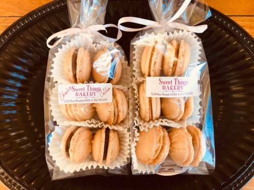 Two bags of macarons from Sweet Things Bakery, neatly packaged with labels, displayed on a black plate.