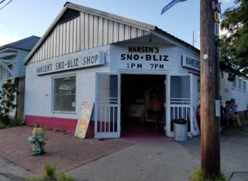 Exterior of Hansen's Sno-Bliz Shop, a colorful building with signs, featuring people outside on a sunny day.