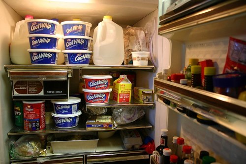 A refrigerator filled with containers of Cool Whip, milk, and various condiments and food items on the shelves.