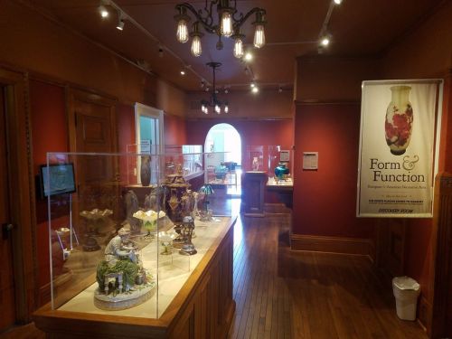 Interior of a museum exhibit featuring decorative art pieces, with display cases and warm red walls.