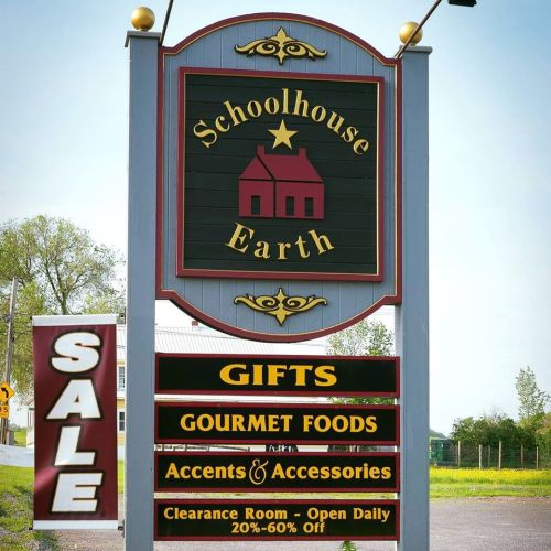 Sign for Schoolhouse Earth featuring "Gifts," "Gourmet Foods," and "Accents & Accessories," with a sale announcement.