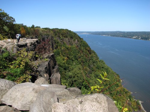 A scenic view of a river bordered by lush green cliffs under a clear blue sky.