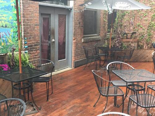 A cozy outdoor patio with metal tables and chairs, surrounded by brick walls and greenery, after a rain.