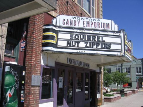 A vintage theater marquee displays "Squirrel Nut Zippers" above the Montana Candy Emporium on a sunny day.