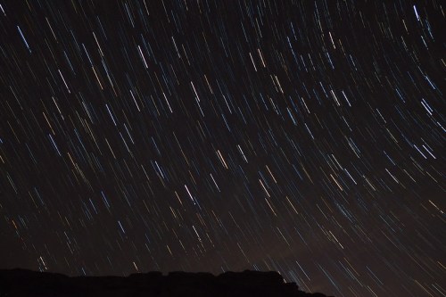 A night sky filled with streaks of stars, creating a dynamic, swirling effect against a dark backdrop.