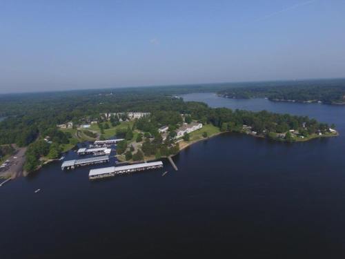 Aerial view of a serene lake surrounded by lush greenery and residential areas, with docks along the shoreline.