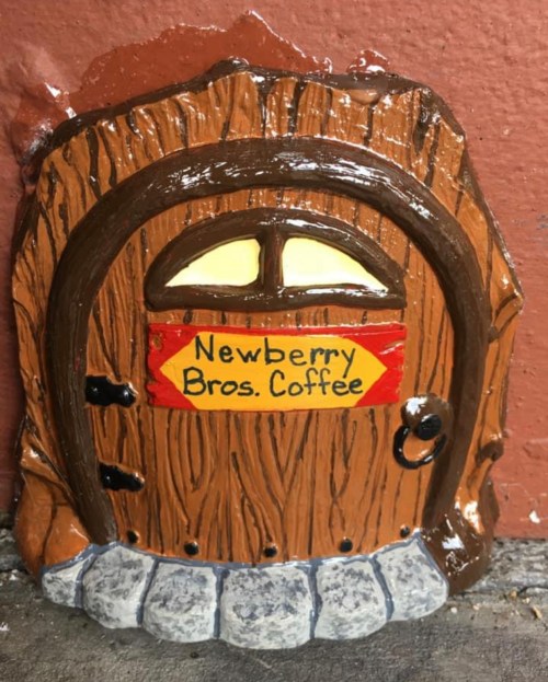 A whimsical, miniature door with a wooden texture and a sign reading "Newberry Bros. Coffee."