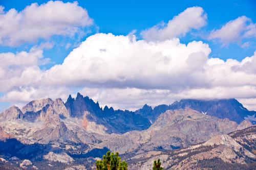 A scenic view of rugged mountains under a blue sky with fluffy white clouds.
