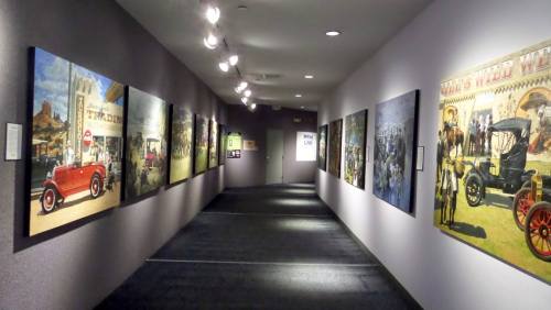 A hallway with framed historical images on the walls, featuring vintage cars and scenes from the past.