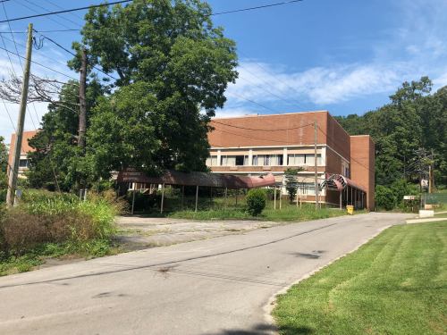 Abandoned building with overgrown vegetation and a clear blue sky in the background.