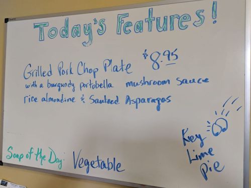 Whiteboard listing today's features: Grilled Pork Chop Plate for $8.95, with sides and Key Lime Pie. Soup of the Day: Vegetable.