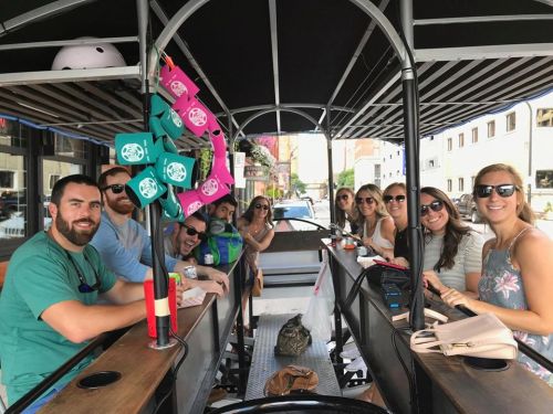 A group of people enjoying a fun outing on a pedal-powered bar, smiling and socializing together.