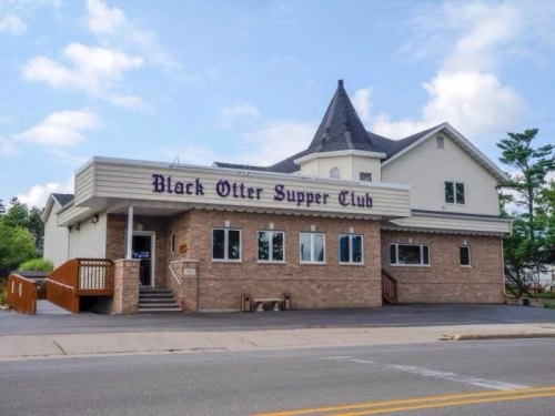 Exterior of the Black Otter Supper Club, a two-story building with a peaked roof and large windows.