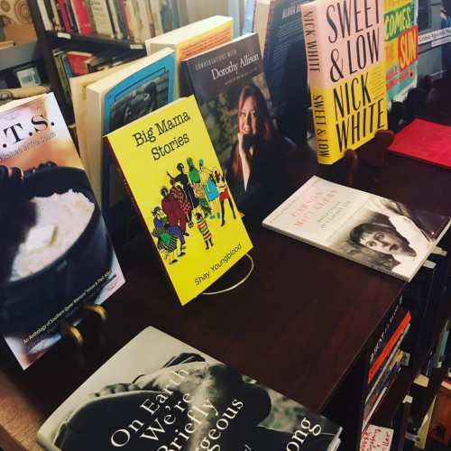 A display of books on a wooden shelf, featuring titles like "Big Mama Stories" and "Sweet & Low."