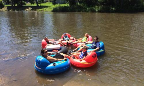 A group of people relaxing on colorful inner tubes in a river on a sunny day.